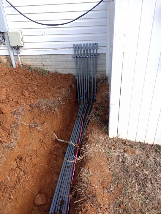 Grouped service conduits routed from an underground trench