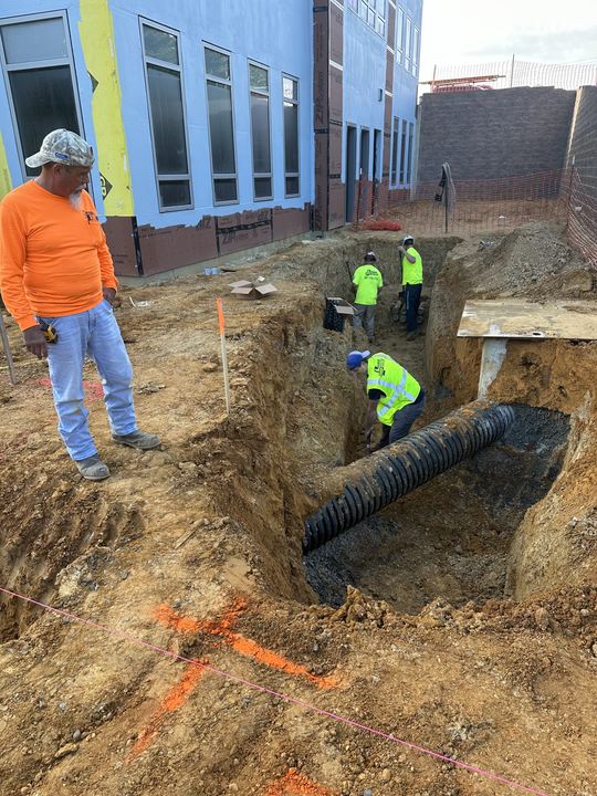 Crew coordinating underground electrical work with site utilities